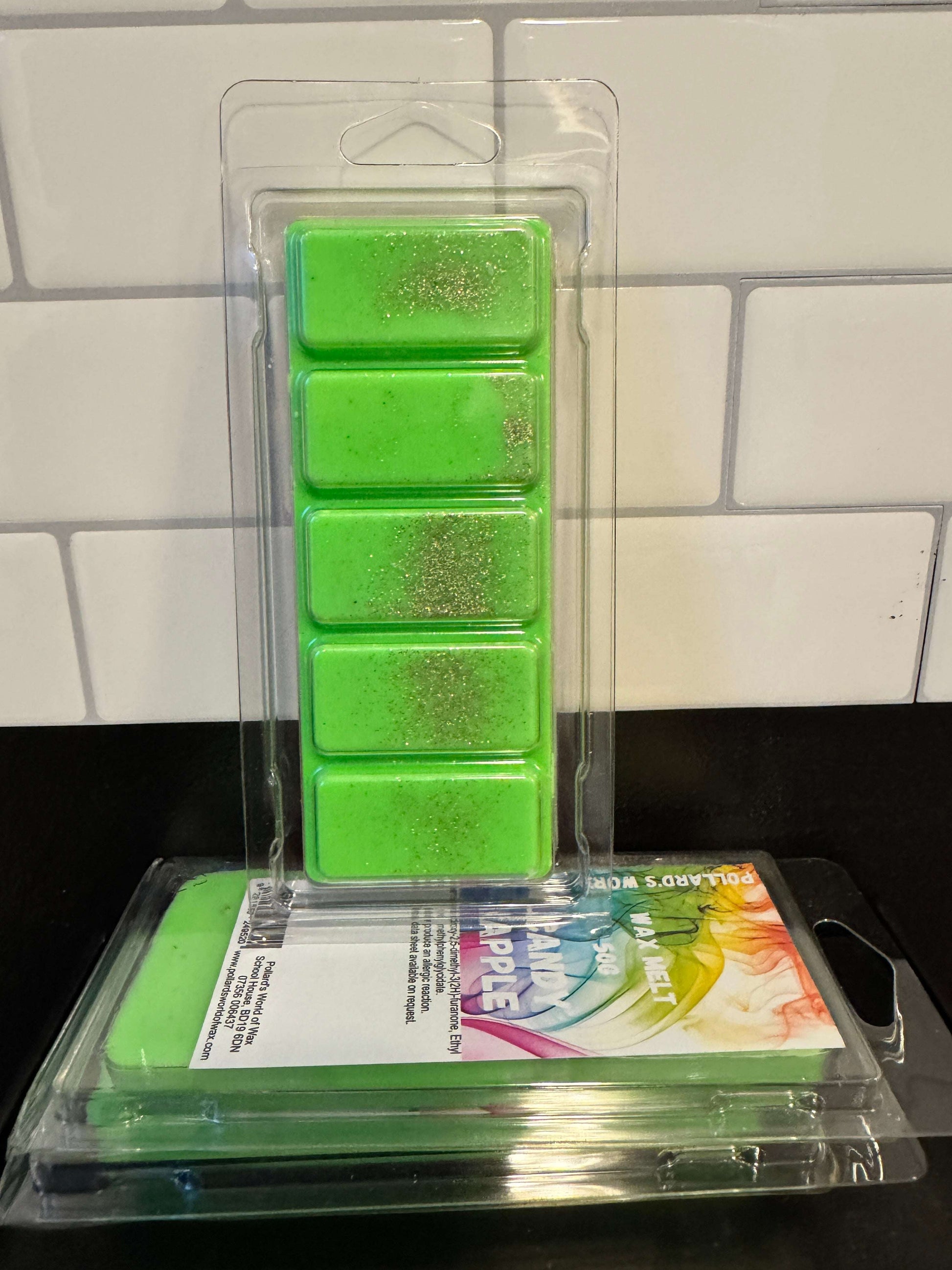 Green wax melts in packaging on a tiled surface
